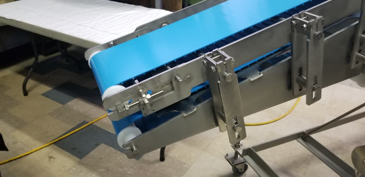 Close-up of a blue conveyor belt and stainless adjustment hardware